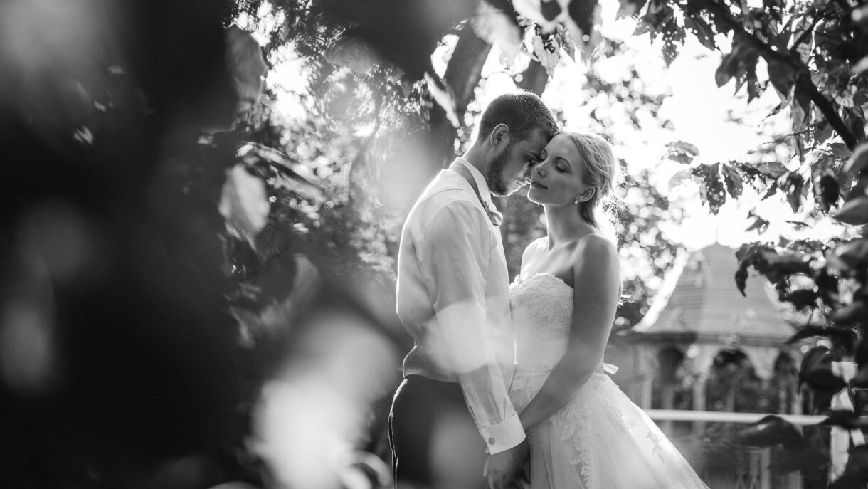 black and white romantic portrait of the bride and groom under the tree holding hands and having a moment together