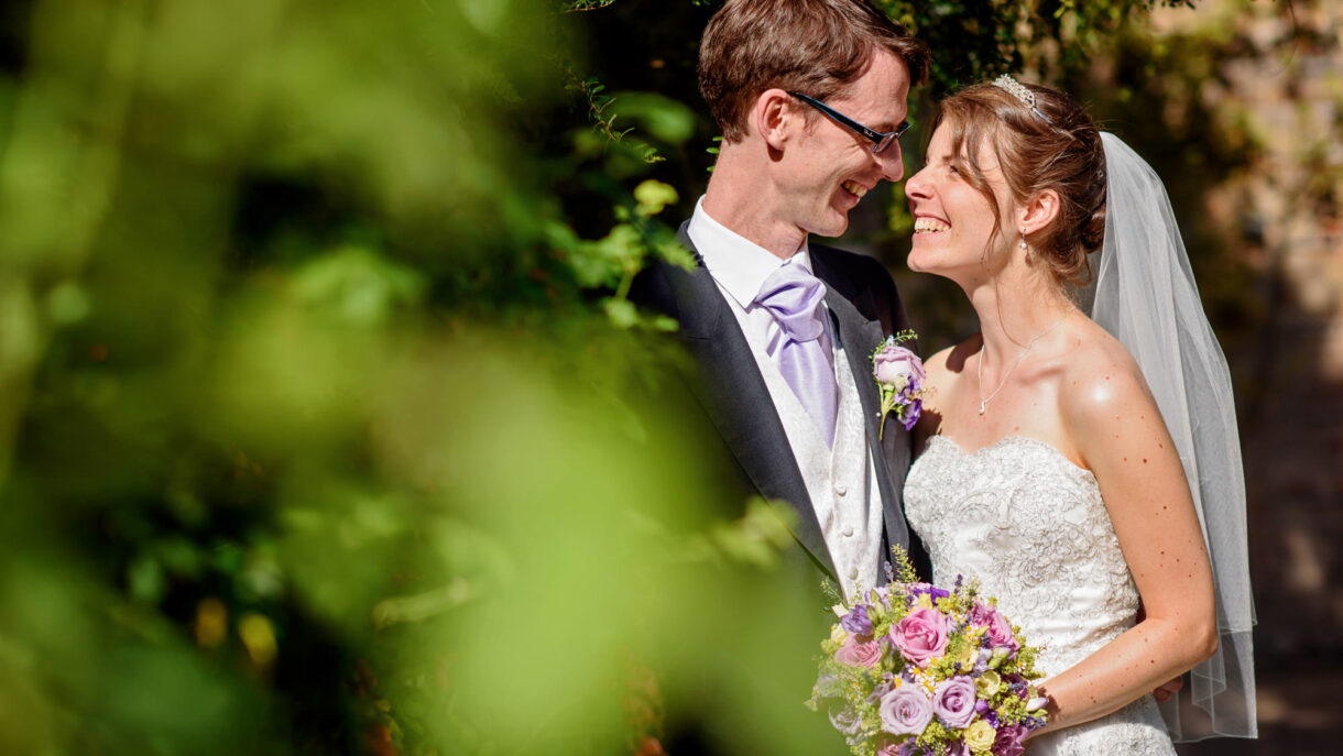 bride and groom surrounded by green leafs