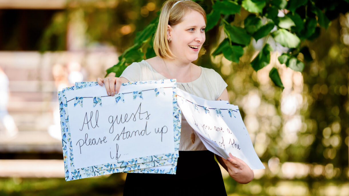 guest holding a sign at the wedding asking guests to stand